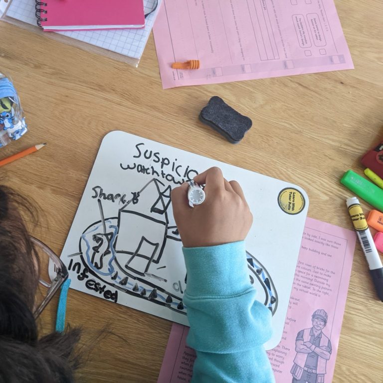 Child drawing on a whiteboard with various coloured markers, surrounded by papers and stationery.