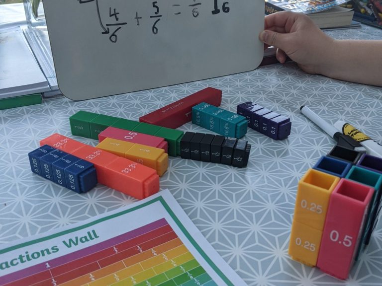 A table with colourful blocks used for teaching fractions and a written equation.
